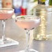 A glass of pink cocktails with blueberries and mint.