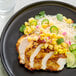A plate of grilled chicken breast topped with mango salsa, served with rice and garnished with cilantro and lime.