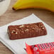 A red package of FULFIL chocolate peanut butter protein bars on a table with a banana.