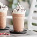 A close up of two Capora Frozen Hot Chocolate Frappes with whipped cream.