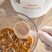 A hand scooping Dr. Smoothie Chocolate Whey Protein Supplement Powder from a white container.