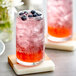 A glass of pink Fanale Blueberry syrup with ice and bubbles.