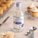 A bottle of McCormick Imitation Coconut Extract next to cupcakes.