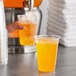 A hand pouring Gatorade orange liquid from a plastic cup.