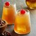 Two glasses of orange drinks with cherries and nuts with DaVinci Gourmet Classic Amaretto Flavoring Syrup.