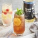 A bottle of Regal Cocktail Cane Sugar Simple Syrup next to a glass of iced tea with straws.