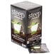 A box of Steep By Bigelow Organic English Breakfast Tea bags on a table with a white cup of tea with green leaves in it.