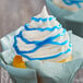 A cupcake with blue and white frosting and blue swirls on top.