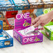 A hand holding a package of ONE Fruity Cereal Protein Bars.