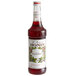 A bottle of Monin huckleberry syrup with a white label and red liquid.