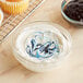 A close up of a cupcake with blue and white frosting and jam on a table.