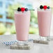 Two glasses of Capora mixed berry smoothies with berries on top.
