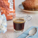 A glass cup of Lavazza Tierra! Brasile espresso on a table with a spoon.