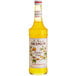 A bottle of Monin Passion Fruit Syrup with yellow liquid.