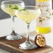 Two glasses of yellow liquid with Monin Passion Fruit Syrup and a half passion fruit on a table.