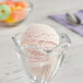 A bowl of strawberry ice cream with a scoop on top.