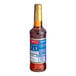 A close up of a Torani Cinnamon Flavoring Syrup bottle with brown liquid inside.