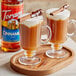 Two glasses of brown liquid with cinnamon sticks and Torani Cinnamon Flavoring Syrup.