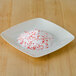 A white plate with Rokz peppermint cocktail rimming sugar with red and white crystals.