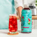 A person holding a bottle of Smartfruit Watermelon Cucumber Mint refresher next to a glass of liquid.