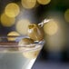A martini with Belosa green olives on a table.