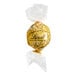 A close up of a Lindt Lindor white chocolate truffle in a gold wrapper.