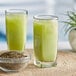 A glass of green ChaTraMue Thai milk tea next to a bowl of green seeds.