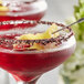 A martini with a red and yellow hibiscus salt flake garnish on the rim.