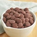 A bowl of Callebaut dark chocolate chips on a wooden table.