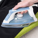 A person holding a white Hamilton Beach iron with blue accents.