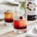 Two glasses of liquid with Monin Cherry Syrup and a cherry on top.