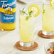 A pair of glasses of lemonade with lemon slices and herbs on a table with a bottle of Torani Sugar-Free Lemon Flavoring.