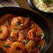 A bowl of rice with a leafy green leaf and shrimp.