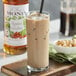 A glass of iced coffee with Monin roasted hazelnut flavoring syrup and a straw.