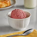 A bowl of Oringer Black Raspberry ice cream with a spoon on a white background.