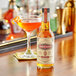 A bottle of Scrappy's Orange Bitters next to a glass of orange liquid on a table.