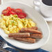 A plate of scrambled eggs and Regal Original breakfast sausages on a table.