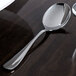 A Oneida stainless steel soup spoon on a table.