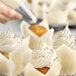 A close-up of a cupcake with ivory whipped cream on top.