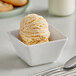 A bowl of peach ice cream with a spoon on a table.