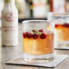 A glass of cranberry bitters with a drink garnished with cranberries and rosemary.