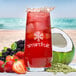A glass of red Smartfruit Renew Strawberry Acai Refresher with ice and fruit.