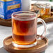 A glass mug of Twinings Lady Grey tea on a wooden tray.