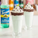 Two glasses of milkshakes with whipped cream and chocolate sprinkles made with Torani Sugar-Free Mint Chocolate Chip Flavoring Syrup.