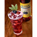 A glass of red liquid with ice and berries, flavored with Monin Sugar Free Blackberry Syrup.