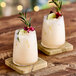 Two glasses of Tiki Breeze White Energy Drink with lime and rosemary on a wooden surface.