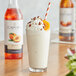 A glass of milkshake with Capora peach flavoring syrup, whipped cream, and peaches.