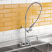 A T&S wall mounted pre-rinse faucet above a sink in a kitchen.
