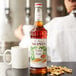 A Monin bottle of Peanut Butter Flavoring Syrup on a white background.