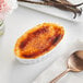 Norohy Organic Madagascar Vanilla Beans in a white bowl with a spoon on a table.